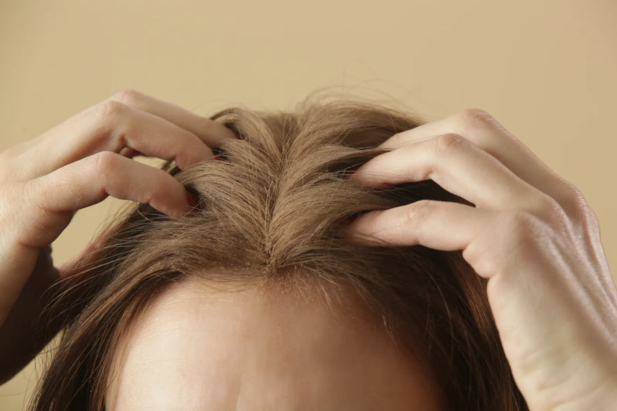 Femme écartant ses cheveux pour masser son cuir chevelu, soin des racines