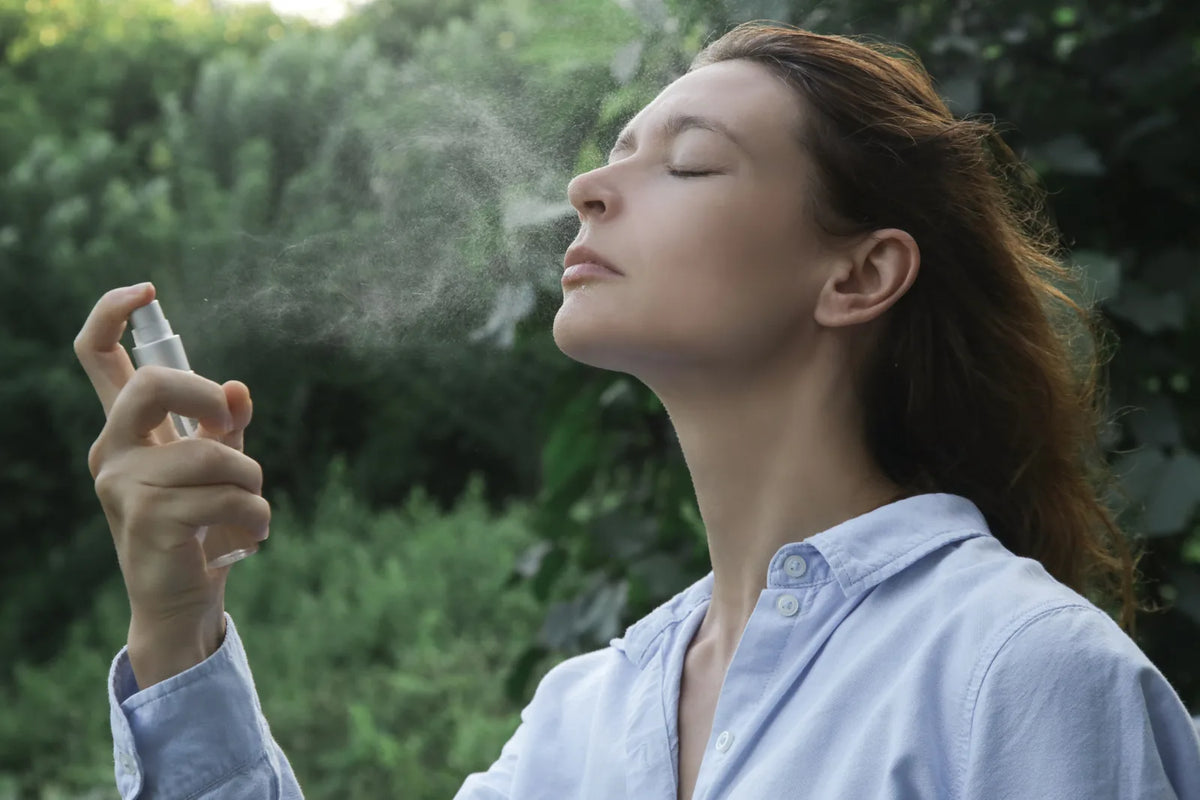Femme vaporisant une brume visage hydratante en lumière naturelle