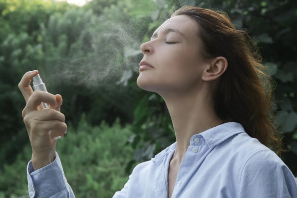 Femme vaporisant une brume visage hydratante en lumière naturelle