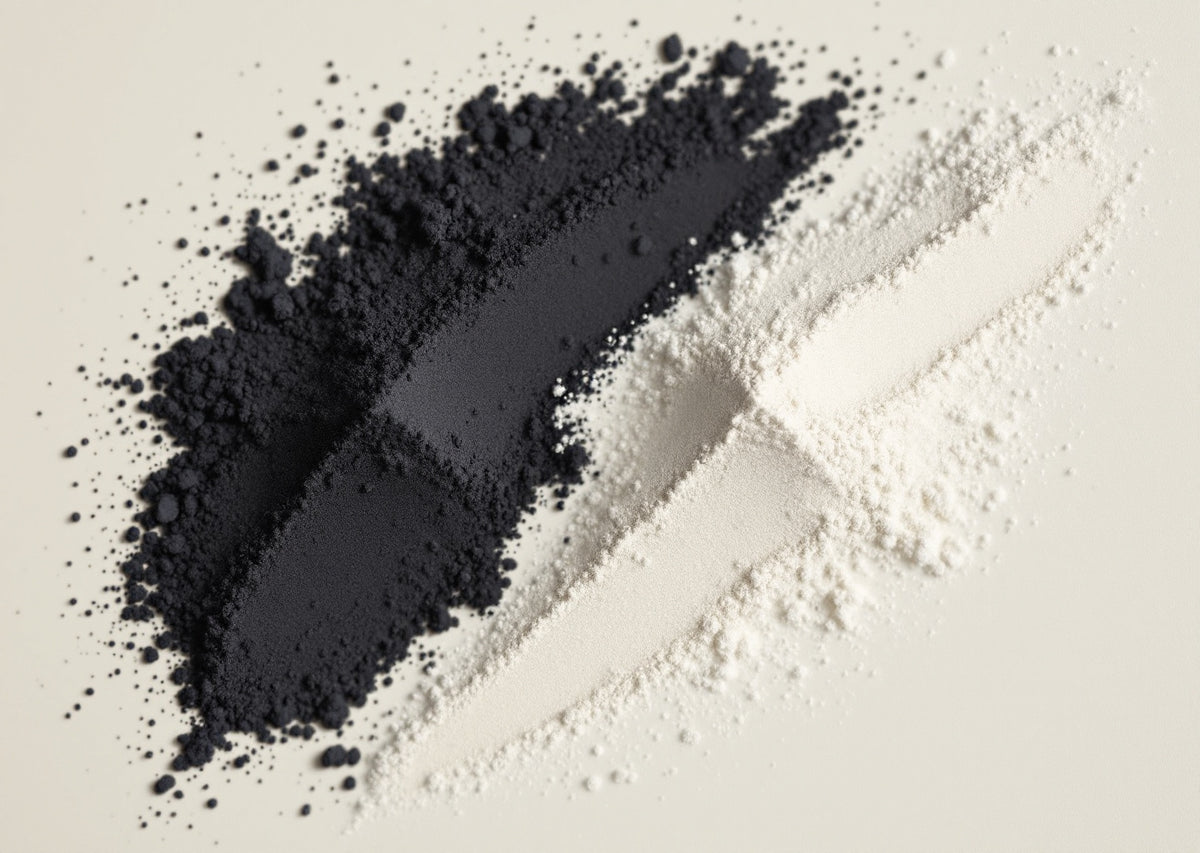 Deux poudres balayées côte à côte, charbon noir et argile claire, sur fond crème — CAMENYS