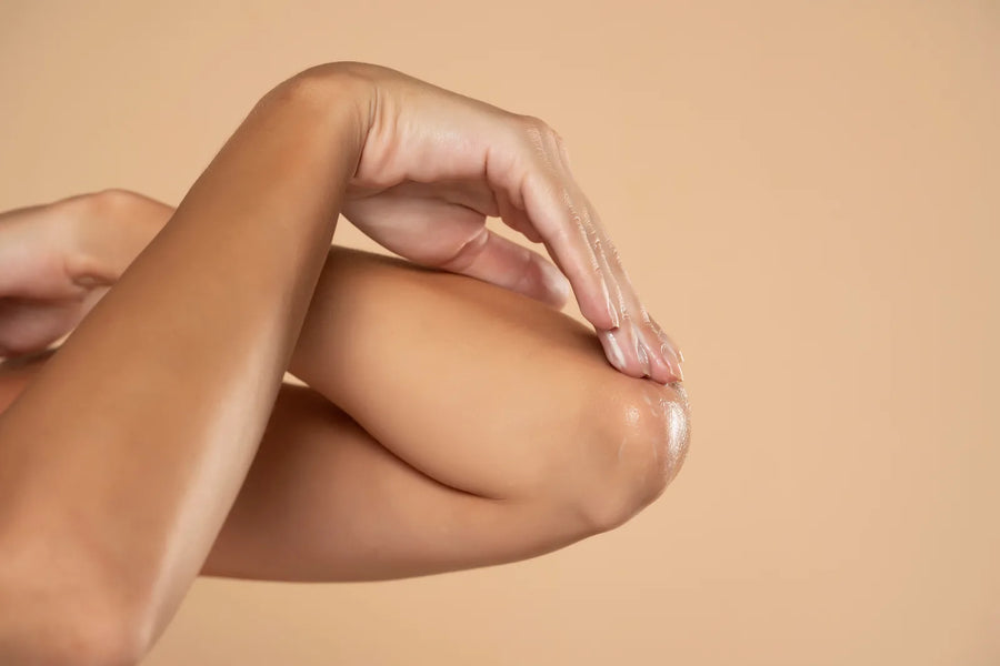 Application d'un soin nourrissant sur une peau sèche du corps, gros plan sur le coude, lumière naturelle chaude