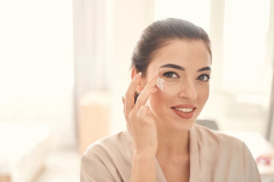 Jeune femme appliquant un soin contour des yeux à la lumière naturelle pour prévenir les premières rides — CAMENYS